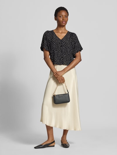 Vrouwenmodel draagt blouse met korte mouwen uit zuiver viscose Model 'GILDA' van Soyaconcept, zwarte stof met witte stippen, slim fit, V-hals met knoopsluiting, kort mouwontwerp met pofmouwen, ruglengte maat S 33 cm, mouwlengte maat S 27 cm, geheelbeeld voorkant.