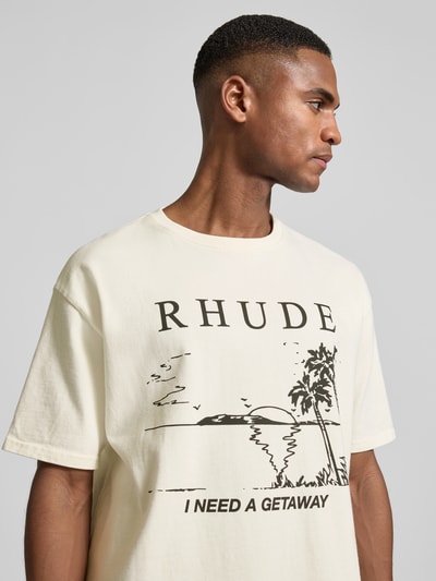 Männermodel trägt Regular Fit T-Shirt mit Logo-Print von RHUDE in Creme, Baumwolle, Motiv-Print und Rundhals, Nahaufnahme Oberkörper.
