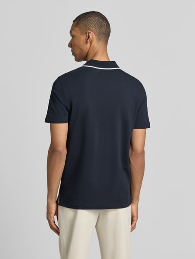 Männermodel trägt Modern Fit Poloshirt mit Logo-Stitching von Christian Berg Men, reine Baumwolle, krój modern fit, polokragen, kolor granatowy, gładka faktura, ganzkörperansicht rückansicht, długość tyłu w rozmiarze M: 71 cm.