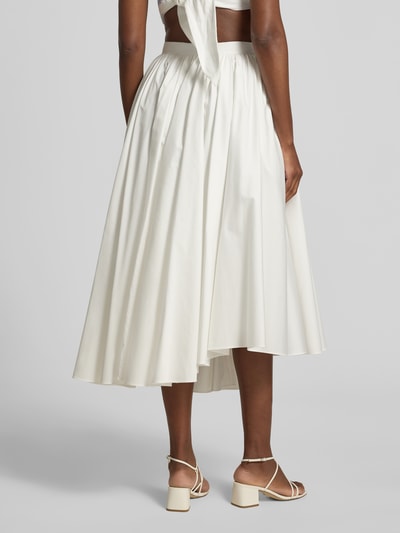 Frauenmodel trägt Midirock aus Baumwolle von Self-Portrait in Creme, Midilänge, Asymmetrischer-Look, Raffung, Nahtreißverschluss, Rückansicht Ganzkörperansicht.