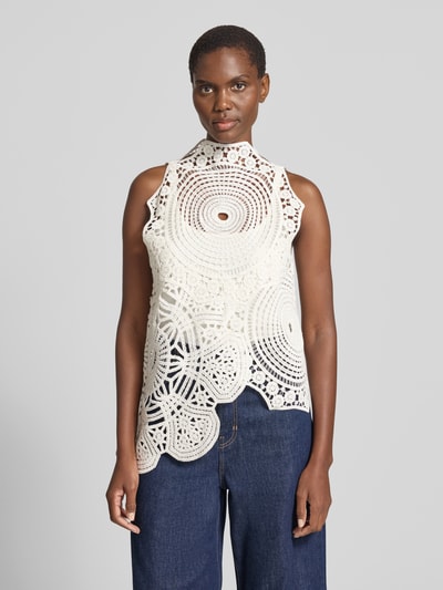 Frauenmodel trägt Stricktop aus Häkelspitze Modell 'CRYSTAL' von Copenhagen Muse in Creme, asymmetrischer Schnitt, Reine Baumwolle, blickdichtes Untertop, Gerade-Form, Rückenlänge bei Größe S: 70 cm, Ganzkörperansicht von vorne.