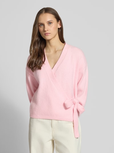 Frauenmodel trägt Regular Fit Cardigan mit Woll-Anteil Modell 'KIRA' von Only in hellem Rosa, Strickoptik, unifarben, Taillengürtel, Nahaufnahme Oberkörper.