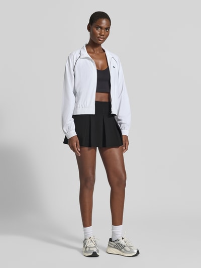 Vrouwenmodel draagt zwarte Ausgestellter Sport-Rock met geïntegreerde fietsbroek van Lacoste, Dames Sport-Rok, volledig vooraanzicht.