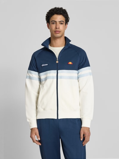 Męski model nosi bluzę rozpinaną z mieszanki bawełny Ellesse model 'RIMINI' niebiesko-kremową, prosty krój, logo, stójka, zamek błyskawiczny, elastyczne wykończenia, długość tyłu 71 cm, długość rękawów 43 cm, ujęcie: całkowity przód