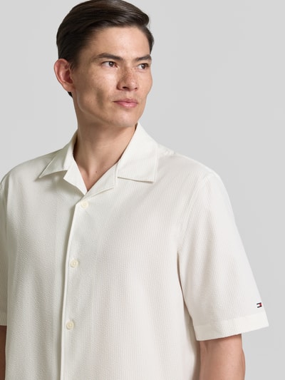 Männermodel trägt Relaxed Fit Freizeithemd aus Seersucker-Material von Tommy Hilfiger in Creme mit Allover-Muster, Nahaufnahme Oberkörper.