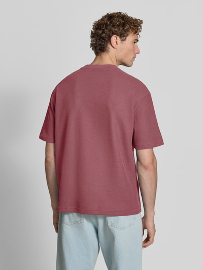 Männermodel trägt Regular Fit T-Shirt aus reiner Baumwolle Modell 'Te_Rib' von BOSS für BOSS Orange in Rot, strukturierte Oberfläche, Ganzkörperansicht Rückansicht.