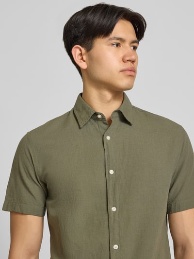 Männermodel trägt Regular Fit Freizeithemd aus Baumwoll-Leinen-Mix von Jack & Jones in Olivgrün, Kentkragen, Nahaufnahme Oberkörper.