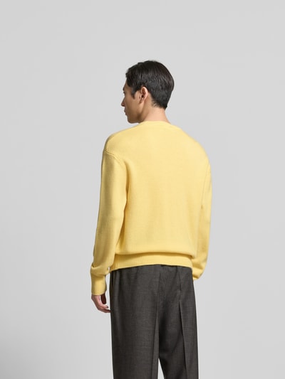 Männermodel trägt Kaschmirpullover in Strick-Optik von Officine Générale, gelb, lockere Passform, gerippte Abschlüsse, Ganzkörperansicht Rückansicht.