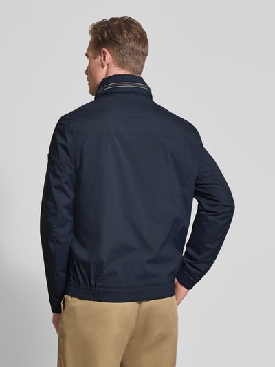 Männermodel trägt Regular Fit Jacke mit Stehkragen van bugatti in donkerblauw met logodetail en elastische mouwboorden, rugaanzicht