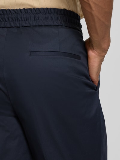 Männermodel trägt Slim Fit Bundfaltenhose aus Baumwoll-Mix Modell 'GETLIN251F3' von HUGO in Dunkelblau, Detailaufnahme Rückansicht.