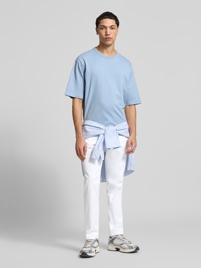 Männermodel trägt Slim Fit Stoffhose mit Gesäßtaschen Modell 'Marco' von Jack & Jones, weiße Baumwollhose, Ganzkörperansicht von vorne.