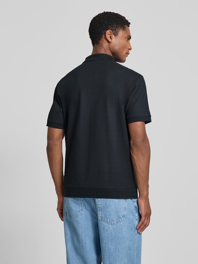 Männermodel trägt Regular Fit Poloshirt mit Strukturmuster Modell 'Tibaris' von JOOP! COLLECTION, Label-Stitching, Polokragen, Reißverschluss, schwarze Farbe, Rückenlänge bei Größe M 70 cm, Ganzkörperansicht Rückansicht.