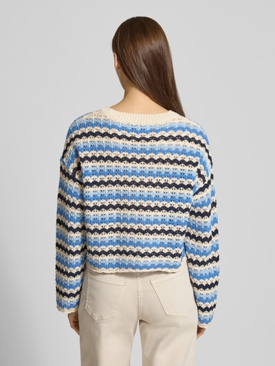 Frauenmodel trägt Regular Fit Strickpullover aus Baumwoll-Mix Modell 'ASA' von ONLY, mehrfarbig gestreift, Lochstrickmuster, Cropped Länge, Muschelsaum, Ganzkörperansicht Rückansicht.