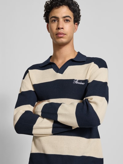 Männermodel trägt Regular Fit Strick-Poloshirt mit Block-Streifen von REVIEW aus reiner Baumwolle, Logo-Bestickung, Nahaufnahme Oberkörper.