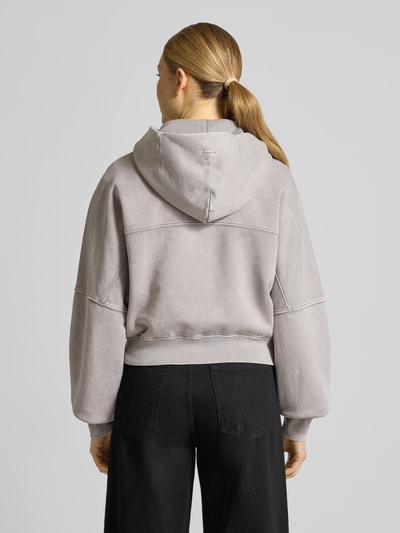 Frauenmodel trägt Sweatjacke mit Zweiwege-Reißverschluss Modell 'RANERA' von Drykorn aus Reine Baumwolle, Relaxed-Fit, Kapuze, Ganzkörperansicht Rückansicht.