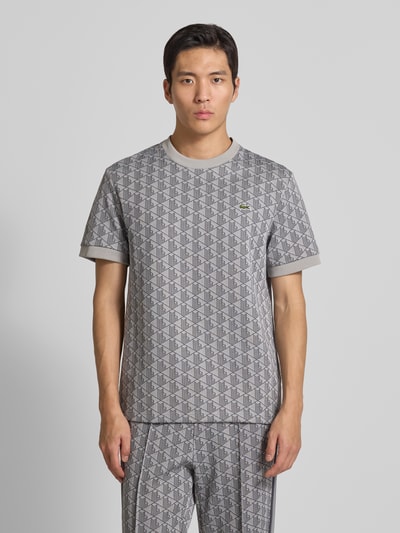 Männermodel trägt Regular Fit T-Shirt mit Baumwoll-Anteil von Lacoste, Optik: Unifarben, Muster: L-Monogramm, Logo-Patch, Ganzkörperansicht von vorne.