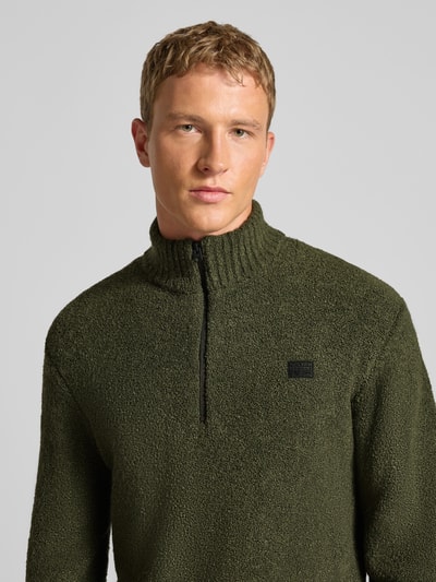 Männermodel draagt Gebreide pullover met labeldetail van G-star, materiaalmix met viscose, los model, opstaande kraag, ritssluiting, ribboorden, Nahaufnahme Oberkörper.