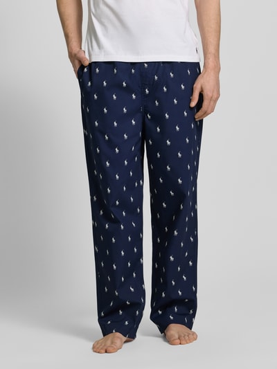 Męski model nosi Comfort Fit Pyjama-Hose aus reiner Baumwolle Modell 'PJ PANT-SLEEP-BOTTOM' od Polo Ralph Lauren Underwear, granatowy kolor, wzór Polo-Pony, wygodny krój, elastyczny pas z troczkiem, boczne kieszenie, materiał bawełna, pełna długość, widok z przodu, ujęcie całej sylwetki.