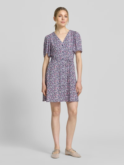 Frauenmodel trägt Leicht ausgestelltes Minikleid aus reiner Viskose Modell 'ALBA' von Vero Moda, Optik: Unifarben, Passform: leicht ausgestellt, Mini-Länge, Ausschnitt: V-Ausschnitt, Details: Taillengürtel, Verschluss: Knopfleiste, Ärmelform: Kurzarm, weite Ärmel, Material: reine Viskose, Ganzkörperansicht von vorne.