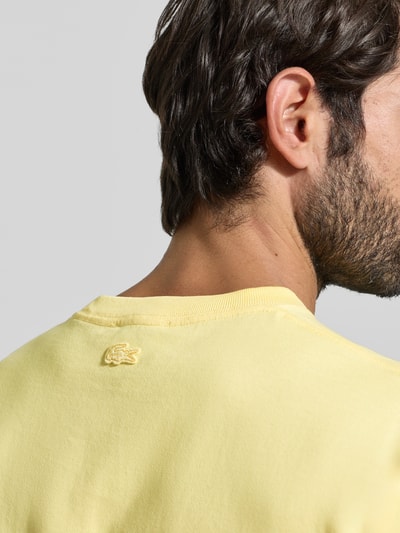Mężczyzna nosi Regular Fit T-Shirt aus reiner Baumwolle Modell 'JERSEY LOURD' od Lacoste, żółty, gładki jersey, krótki rękaw, detal logo, detaliczny widok na górę pleców.