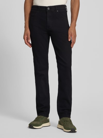 Männermodel trägt Straight Fit Jeans im 5-Pocket-Design Modell 'Greensboro' von Wrangler in Schwarz, Baumwoll-Mix mit Stretch-Anteil, Gerader-Schnitt, Knopf-Reißverschluss, Ganzkörperansicht von vorne.