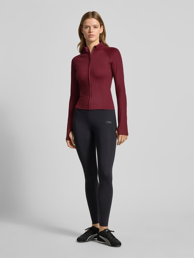 Vrouwenmodel draagt Slim Fit Sweatjacke met Stehkragen Modell 'Yoga' van Gina Tricot, bordeauxrood, elastische stof, voorkant, volledige lichaamsweergave.