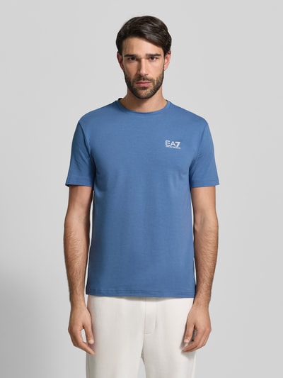 Männermodel trägt Regular Fit T-Shirt mit Logo-Print von EA7 Emporio Armani, blauer Baumwoll-Mix, Rundhalsausschnitt, Ganzkörperansicht von vorne.