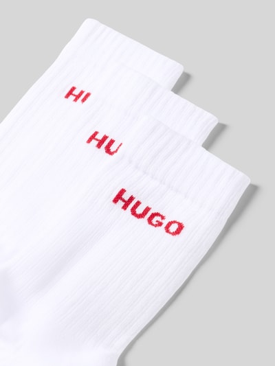 Productfoto, witte sokken van katoenmix met rode HUGO letters, geribbelde textuur, uniseks accessoire, detailopname