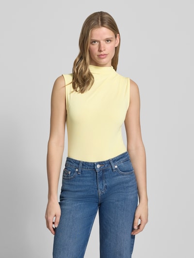 Frauenmodel trägt Shaped Fit Shirt ohne Ärmel Modell 'MADISON' von Pieces in Unifarbe Gelb, hochgeschlossen, Label Stitching, Ganzkörperansicht von vorne.