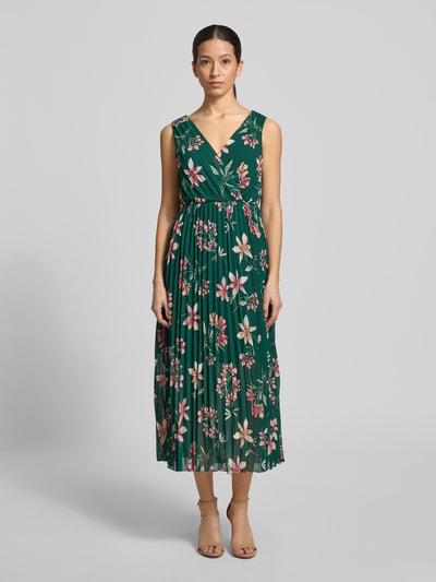 Modelka kobieca nosi Midikleid mit Plisseefalten und V-Ausschnitt od Apricot, zielony szyfon z kwiatowym wzorem, długość tyłu 122 cm, szerokość w rozmiarze S: 32 cm, krój A-linia, całościowy look, widok całej sylwetki z przodu.