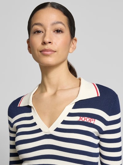 Frauenmodel trägt T-Shirt aus Viskose-Mix in Strick-Optik Modell 'Kolo' von JOOP! mit 3/4-Arm, Umlegekragen, Label-Stitching, eng anliegender Passform, gestreift in Blau und Creme, Nahaufnahme Oberkörper.