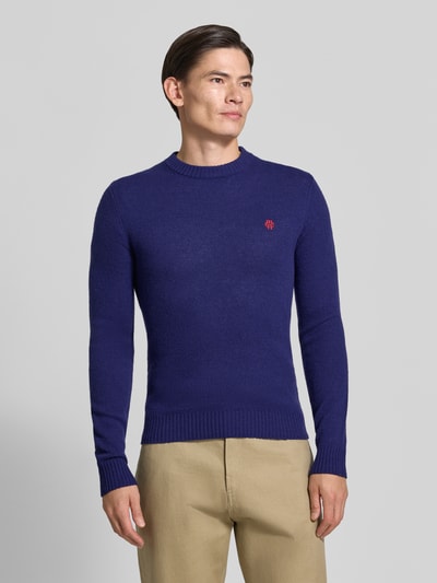 Männermodel trägt Slim Fit Strickpullover aus reiner Wolle mit Label-Stitching von MCNEAL, marineblau, gerippte Abschlüsse, Ganzkörperansicht von vorne.