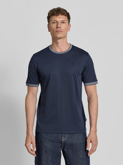 Męski model nosi T-Shirt mit Rundhalsausschnitt od bugatti, bawełniany miks, krój regular fit, detal z logo, długość tyłu w rozmiarze M: 70 cm, widok całej sylwetki od przodu.