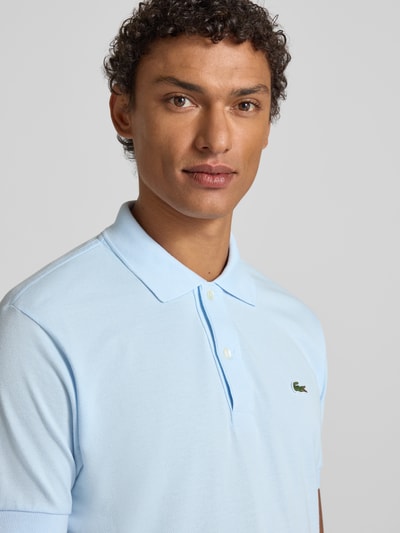 Männermodel trägt Poloshirt mit Label-Stitching Modell 'L.12.12 CORE' von LACOSTE aus reiner Baumwolle im Unifarbenen-Design, Nahaufnahme Oberkörper.