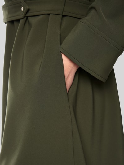 Frauenmodel trägt Knielanges Kleid mit Stehkragen und Gürtel von Marc Cain in Olivgrün, feine Struktur, Material-Mix, Detailaufnahme.