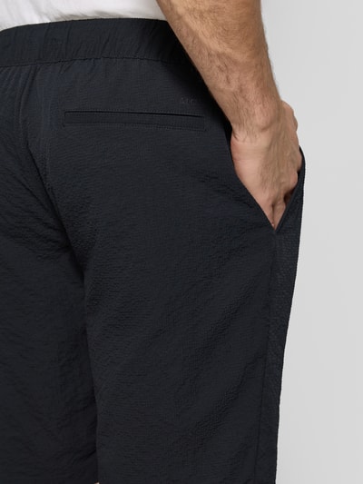 Männermodel trägt Shorts mit elastischem Bund und Eingrifftaschen von MCNEAL, dunkle Farbe, Strukturmuster, Detailaufnahme Rückenansicht. Regular Fit, Gesäßtaschen, Tunnelzug, Bundweite 44 cm, Innenbeinlänge 26 cm.