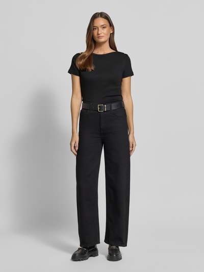 Frauenmodel trägt Slim Fit T-Shirt aus reiner Baumwolle von Tommy Hilfiger in Schwarz, unifarben, mit U-Boot-Ausschnitt, Logo-Detail und Zierknöpfen; kurzarm, Webware-Struktur, Ganzkörperansicht von vorne.