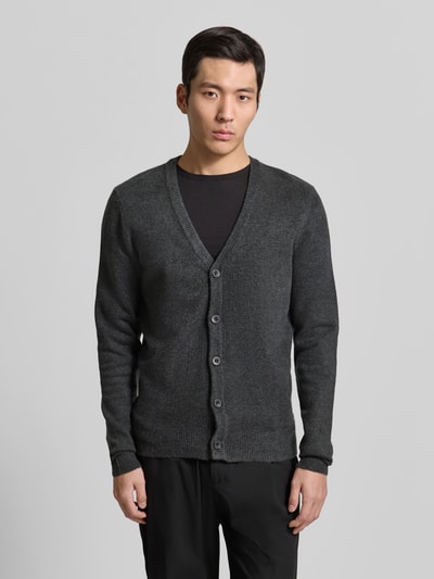Männermodel trägt Strickjacke mit Knopfleiste Modell 'HEINE' von Casual Friday in Dunkelgrau, gerippte Abschlüsse, Ganzkörperansicht von vorne.