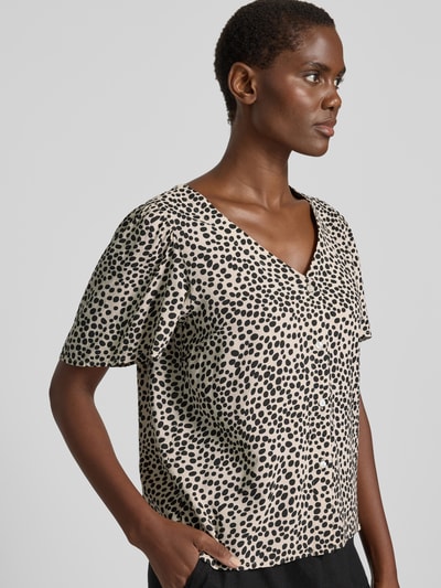 Frauenmodel trägt Bluse mit V-Ausschnitt Modell 'GRACE' von Vila, beige mit schwarzen Punkten, Straight Fit, Knopfleiste, Nahaufnahme Oberkörper.