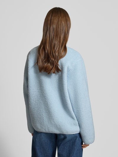 Frauenmodel trägt Relaxed Fit Fleecejacke mit Stehkragen Modell 'VERA' von JJXX aus hellblauem Teddyfell, Rückenlänge 57 cm, Ganzkörperansicht Rückansicht.