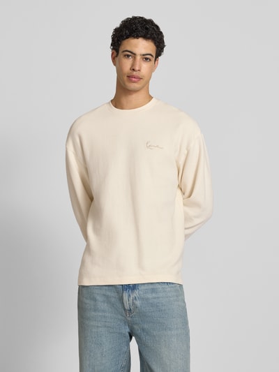 Männermodel trägt Regular Fit Sweatshirt mit Strukturmuster von KARL KANI in Beige, Reine Baumwolle, Logo-Stitching, Rundhalsausschnitt, elastische Ärmelabschlüsse, Ganzkörperansicht von vorne.