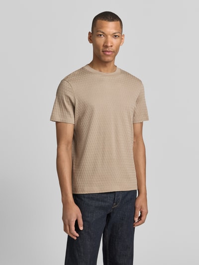 Männermodel trägt T-Shirt mit Strukturmuster Modell 'Raulos' von JOOP! Collection aus reiner Baumwolle, Modern Fit, Rundhalsausschnitt, Label-Detail, beige, Ganzkörperansicht von vorne.
