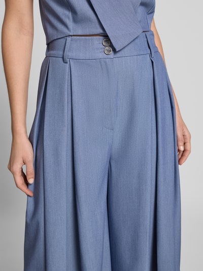 Frauenmodel trägt Culotte mit Biesen und Eingrifftaschen von Rinascimento in Hellblau, Material-Mix mit Viskose, Nahaufnahme Oberkörper.