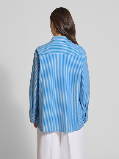 Frauenmodel trägt Oversized Langarmbluse aus Baumwoll-Mix von Tommy Hilfiger in Blau-Weiß mit feinem Streifenmuster, Ganzkörperansicht Rückansicht.