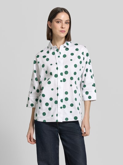 Frauenmodel trägt Relaxed Fit Hemdbluse mit 3/4-Arm von Christian Berg Woman aus reiner Baumwolle mit grünen Punkten, durchgehende Knopfleiste, Hemdblusenkragen, Rückenlänge 57 cm, Ärmellänge 65 cm, Ganzkörperansicht von vorne.