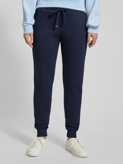 Frauenmodel trägt Sweatpants mit elastischem Bund von Christian Berg Woman aus Baumwoll-Mix, lockerer Schnitt, Tunnelzug, französische Eingrifftaschen, marineblau, Ganzkörperansicht von vorne.