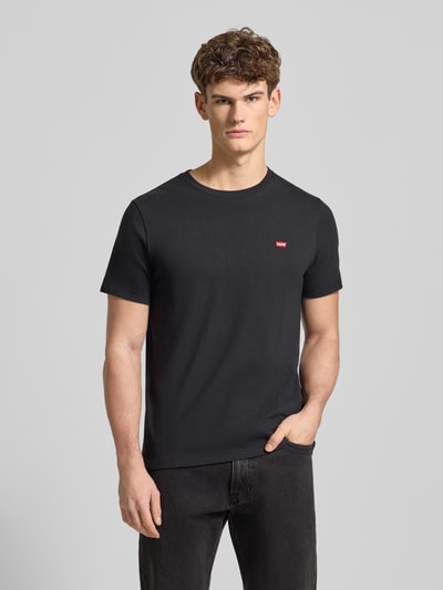 Męski model nosi T-Shirt mit Label-Stitching od Levi's®, czarna bawełna, regular fit, okrągły dekolt, widok całej sylwetki z przodu.