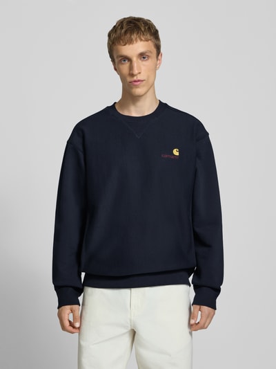 Männermodel trägt Regular Fit Sweatshirt mit Logo-Stitching von Carhartt Work In Progress in Dunkelblau, Baumwoll-Mix, Rundhalsausschnitt, elastische Abschlüsse, Ganzkörperansicht von vorne.