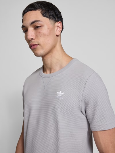 Männermodel trägt Regular Fit T-Shirt mit Baumwoll-Anteil von adidas Originals, Optik: Unifarben, Waffel-Struktur, Logo-Stitching, Rundhals, Kurzarm, Nahaufnahme Oberkörper.