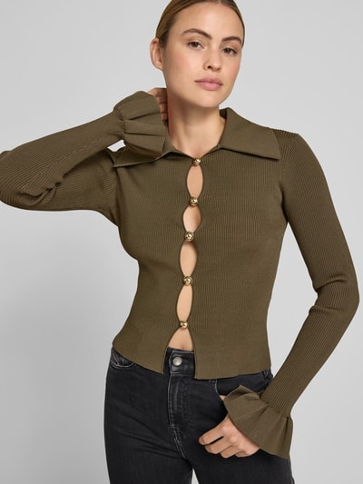 Frauenmodel trägt Slim Fit Bluse aus Viskose-Mix von Self-Portrait in Strick-Optik mit Cut-Outs, Olivgrün, Langärmelig, Nahaufnahme Oberkörper.